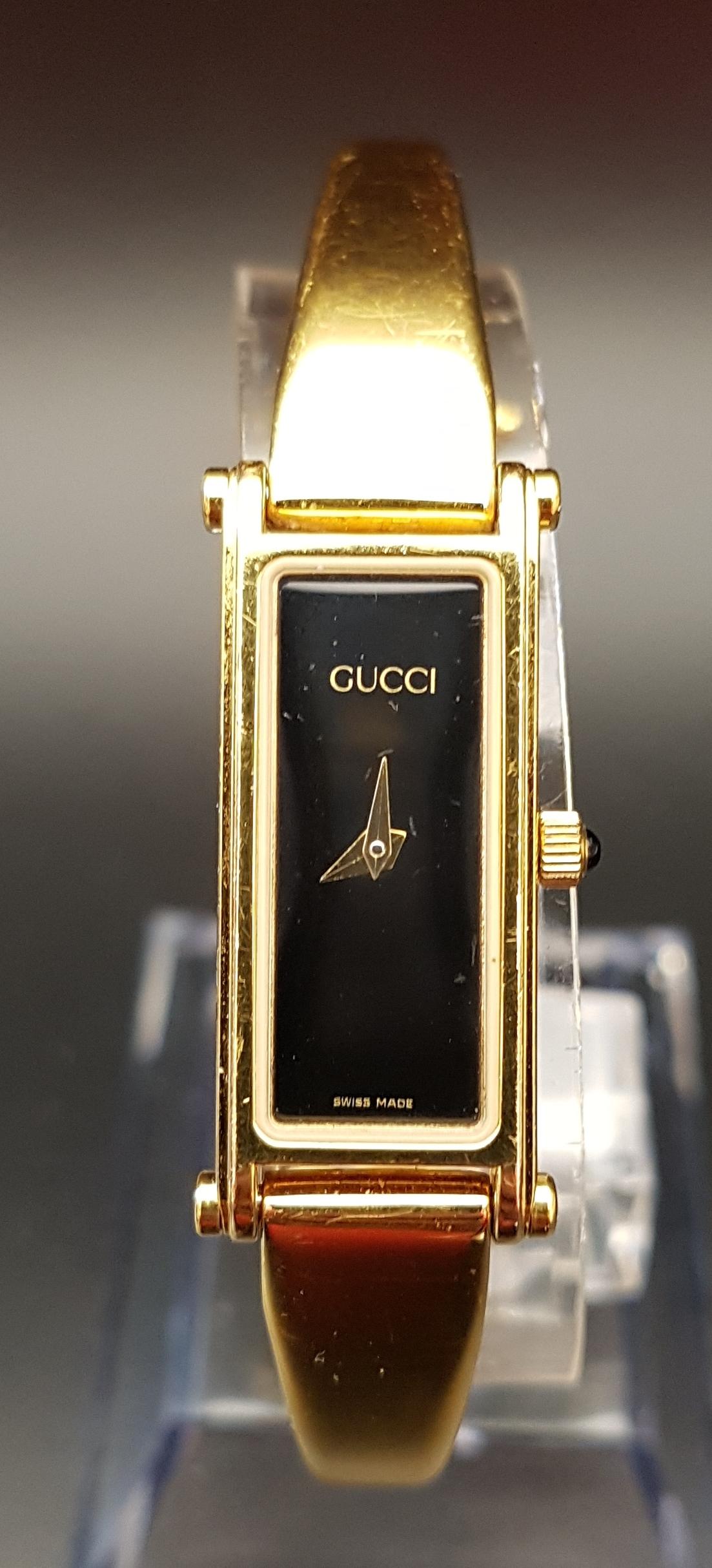 LADIES GUCCI 1500 WRISTWATCH the gold plated watch with black rectangular dial, the hinged