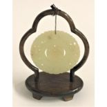 JADEITE MEDALLION of circular form with pierced decoration on a later stand, 5.5cm diameter