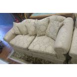 A TWO SEATER SETTEE, the double scroll back with scrollover arms and loose cushions,