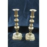 A PAIR OF 19TH CENTURY BRASS CANDLE STICKS each with a knopped and facet column on rectangular base