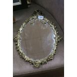 A BRASS FRAMED MIRROR the oval plate within a ribbon tied and foliate frame 44cm (h) x 35cm (w)