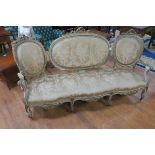 A 19TH CENTURY GILTWOOD AND POLYCHROME TRIPLE CHAIR BACK SETTEE with ribbon tied cresting above