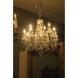 A CONTINENTAL SILVERED AND CUT GLASS TWELVE BRANCH CHANDELIER hung with faceted pendant drops