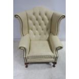 A PAIR OF HIDE UPHOLSTERED WINGED CHAIRS with deep buttoned upholstered back and loose cushion with