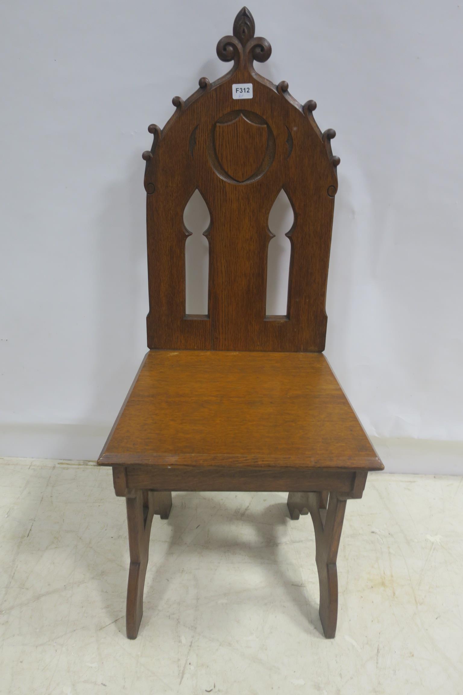 A GOTHIC DESIGN OAK HALL CHAIR with pierced tracery back above a panelled seat on splayed legs