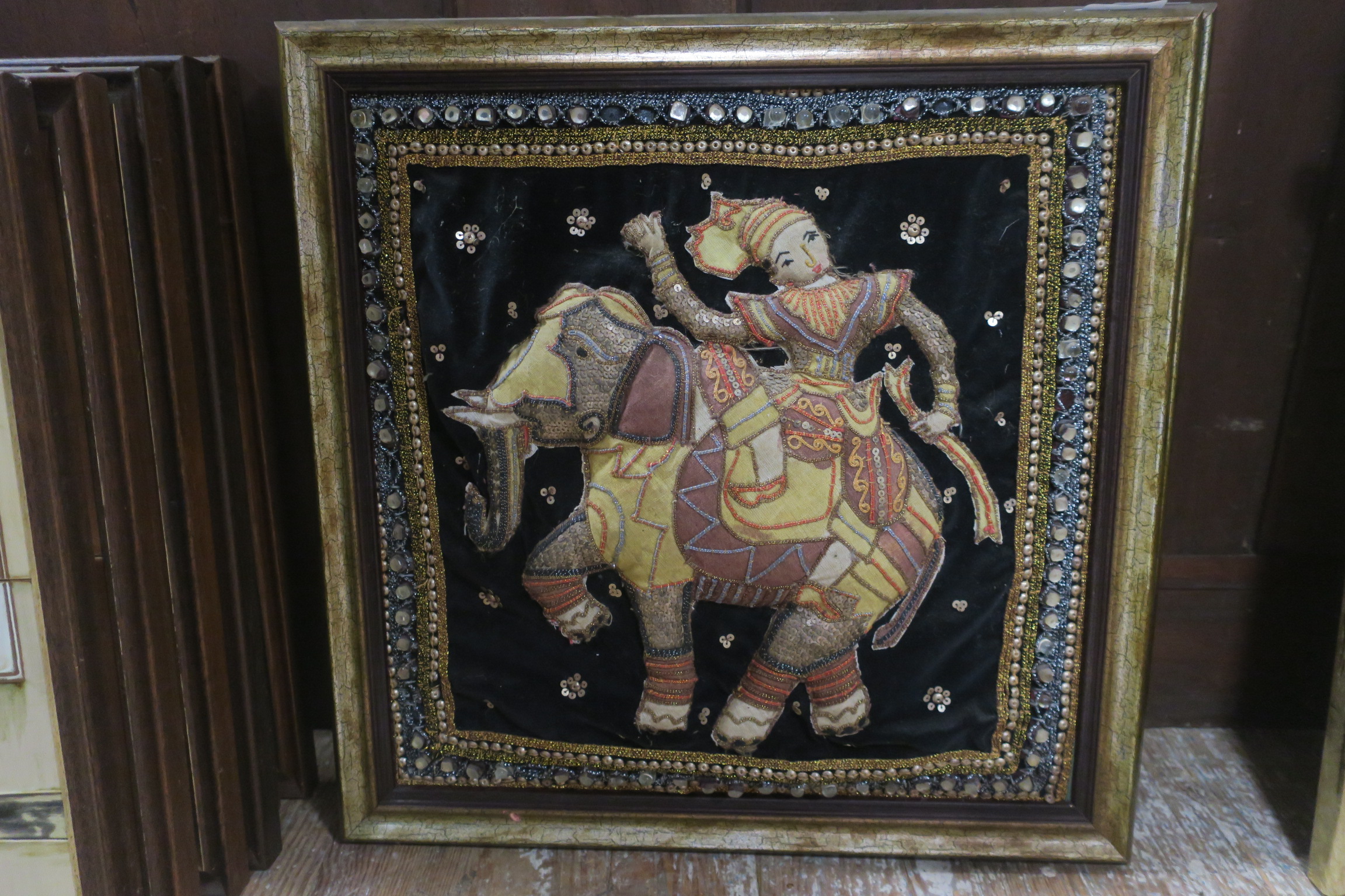 A PAIR OF INDIAN TAPESTRIES depicting figures sitting on an elephant and a horse in gilt frames