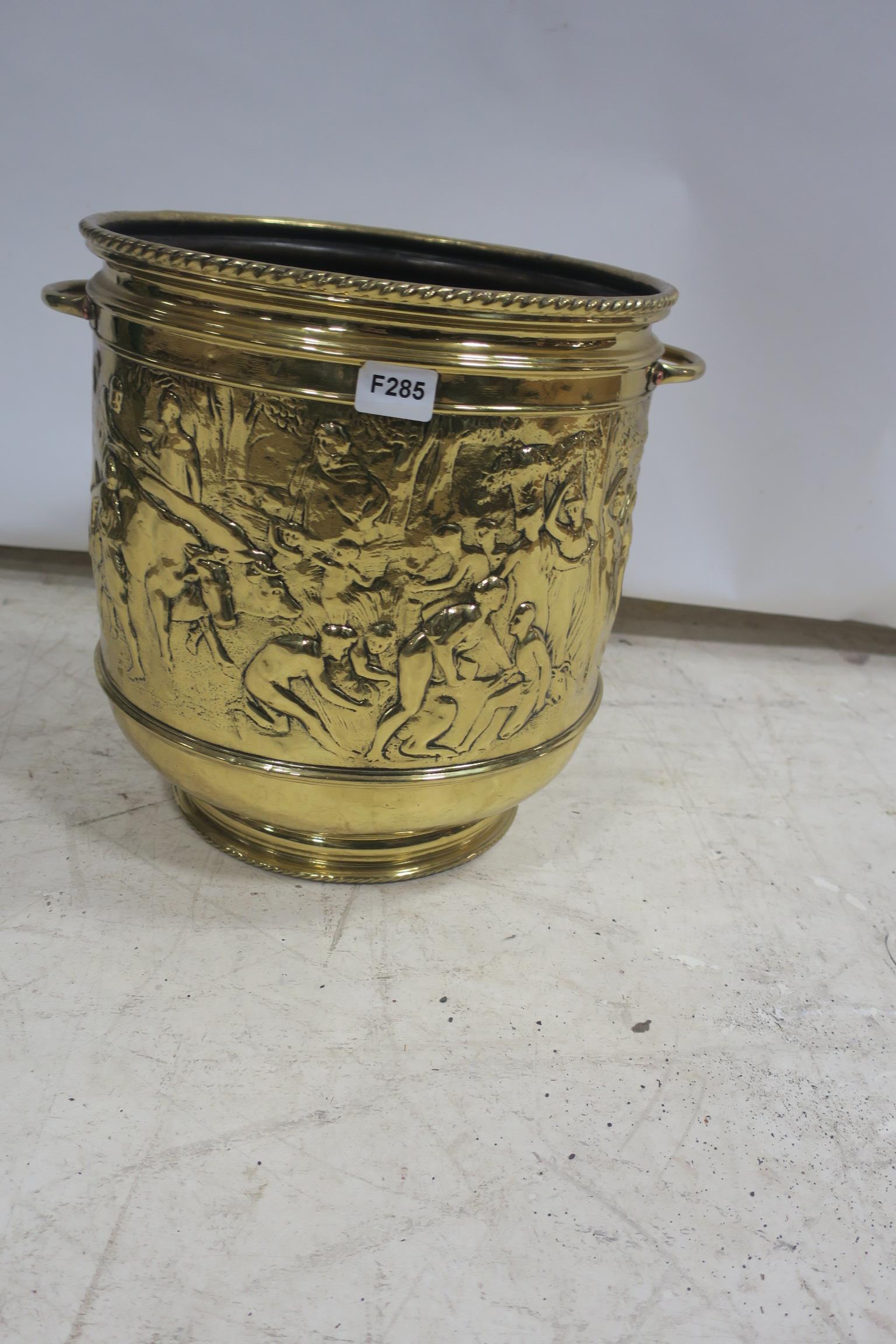 A BRASS EMBOSSED JARDINIERE of cylindrical outline with carrying handles raised in a circular