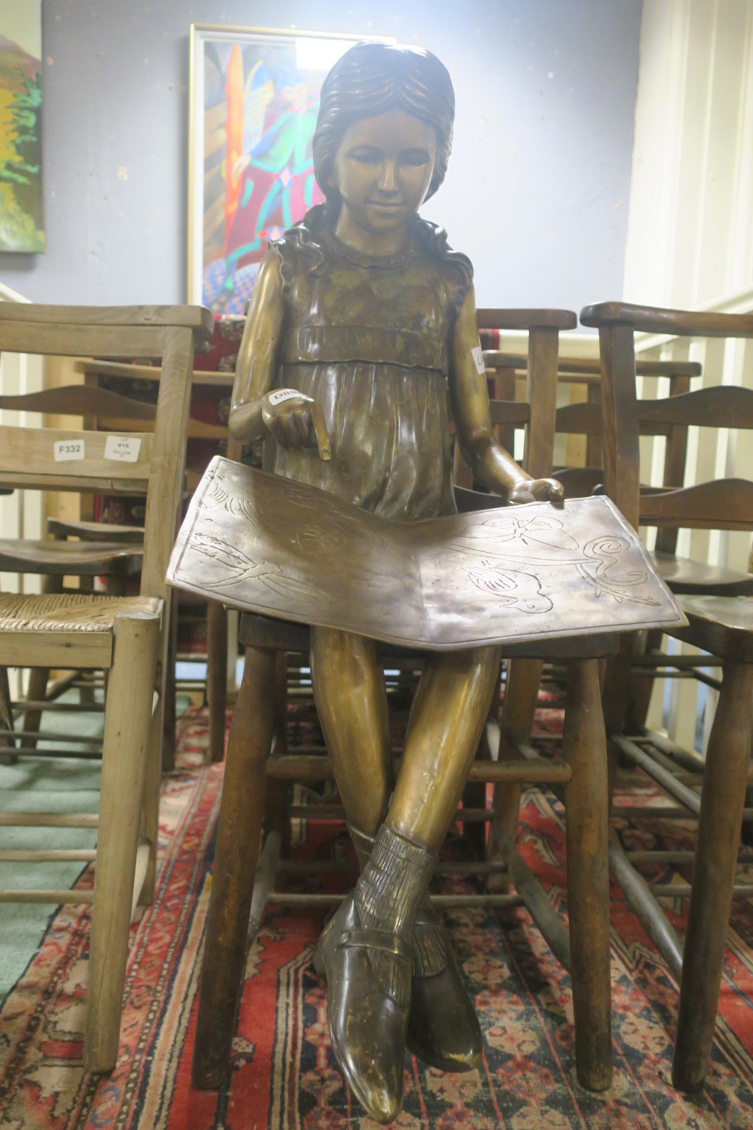 A BRONZE FIGURE modelled as a young female shown seated reading a book