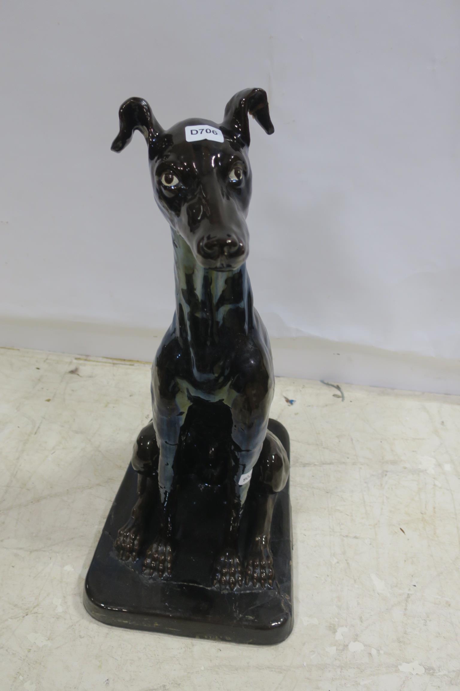 A GLAZED CHINA FIGURE modelled as a hound shown seated on rectangular base 82cm (h) x 36cm (w) x