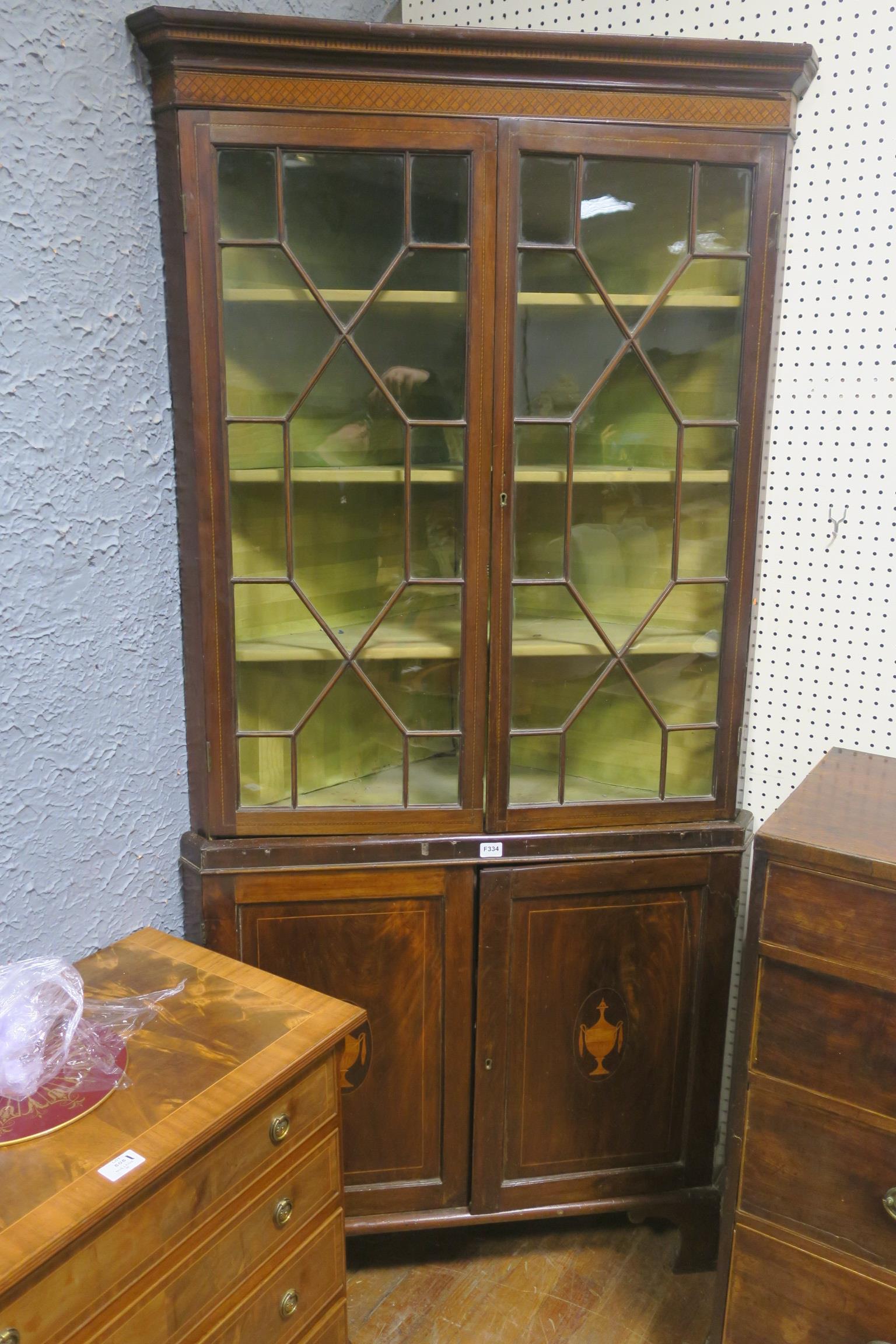 A GEORGIAN MAHOGANY AND SATINWOOD INLAID CORNER CABINET the outswept moulded cornice above a pair