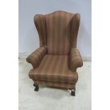 A MAHOGANY AND UPHOLSTERED WINGED CHAIR with scroll over arms and loose cushion on cabriole legs