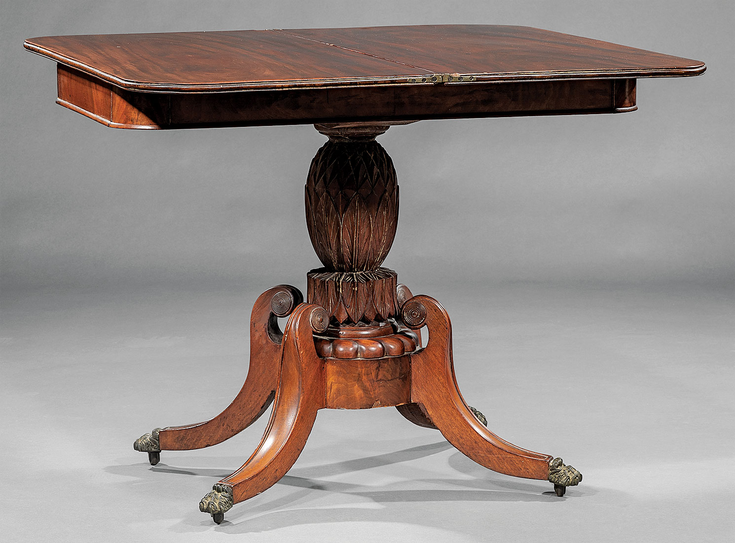 American Classical Mahogany Games Table , early 19th c., foldover swivel top, pineapple-carved