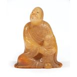 Chinese Shoushan Soapstone Figure of a Luohan, carved seated with arms grasping raised knee, wearing