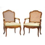 Two Antique Louis XV-Style Carved Fruitwood Fauteuils, shaped floral carved crest rail, caned back