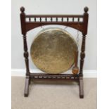 A large Edwardian stained walnut-framed brass dinner gong, with spindled gallery and turned