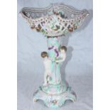 A German porcelain centerpiece with pierced and floral encrusted bowl supported by two putti, on