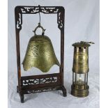 A Chinese brass table gong in the shape of a bell, engraved with mythical beasts and geometric