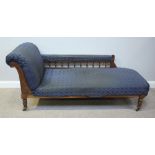 A stained walnut chaise lounge with spindle arm-rail and blue fabric upholstery, raised on turned