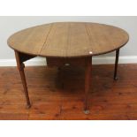 An 18th century oak oval gate-leg, drop-leaf dining table with turned and tapering supports to pad