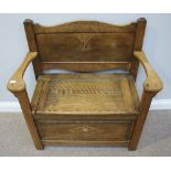 A small single-seat oak settle, with carved back and hinged seat enclosing storage space, raised