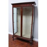 A mahogany two-door glazed display cabinet enclosing three glass shelves, with dentil moulded