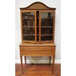 An Edwardian inlaid mahogany cabinet, the top with arched cornice above a pair of glazed doors