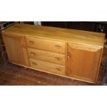 An Ercol light elm 'Windsor' sideboard, with three central graduated drawers, flanked by two