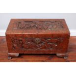 A Chinese camphor wood trunk, ornately carved with scenes of figures and horses battling, raised
