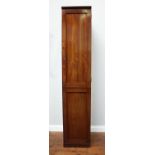 A narrow walnut cupboard, the single panelled door enclosing hanging space, 43cm wide