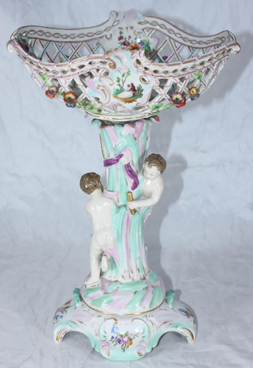 A German porcelain centrepiece with pierced and floral encrusted bowl supported by two putti, on