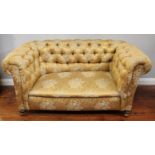 A drop-end Chesterfield style sofa, with gold, floral fabric upholstery, raised on bun feet to