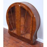 A walnut Art Deco period display cabinet of circular form, with a pair of Sunburst glazed doors