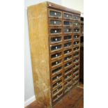 A large haberdashery cabinet of thirty six glass-fronted drawers with metal handles (as found),