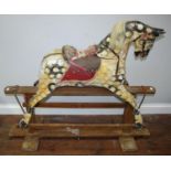 An Edwardian dappled rocking horse, raised on trestle base, leather studded bridle and flower,
