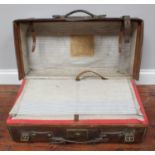 A brown leather suitcase with interior compartments and a label for an Irish auction house 'Fleet