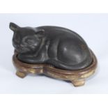 An Oriental patinated bronze figure of a recumbent cat on wooden display stand, approx. 16cm wide