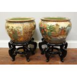 A pair of 20th century Satsuma fish bowls on stained and scrolling wooden stands, 50cm tall