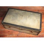 A faded green steamer trunk with brass studded decoration, brass locks and handles to each side, the