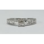 An 18ct white gold solitaire diamond ring, corner set with a princess-cut diamond and channel set