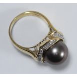 An 18ct gold dress ring set with a central South Sea pearl surrounded by fourteen baguette and