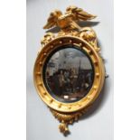 A Regency giltwood and gesso circular convex mirror, with carved eagle pediment, scrollwork and