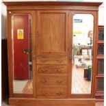 An Edwardian inlaid mahogany triple wardrobe with central cupboard above four drawers, flanked by