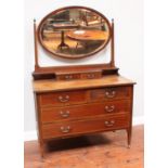 An Edwardian inlaid mahogany dressing table with oval mirror on raised plinth, two short and two