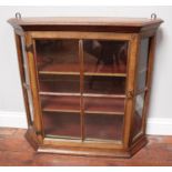 A small oak wall hanging cabinet, the single glazed front door enclosing two shelves, 80cm wide