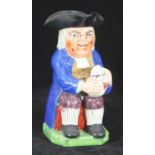 A circa 1820 Toby jug, the character with blue frocked coat, tricorn hat, purple breeches, striped
