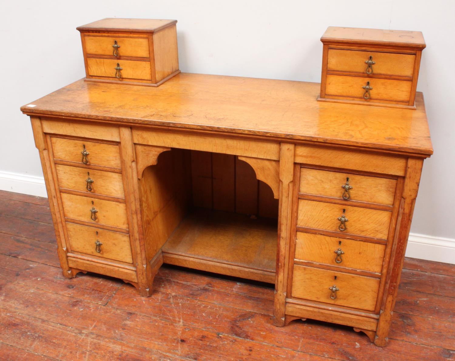 An oak pedestal desk with two miniature cupboards atop either side, the pedestals with four