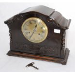 A stained oak mantel clock, the brass dial with Roman numerals denoting hours and outer chapter