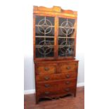 A Regency mahogany secretaire bookcase, with brass-inlaid shaped cornice above a pair of circular