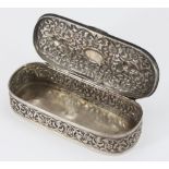 A late 19th century Indian silver oval trinket box and cover, ornately chased with scrolling Islamic