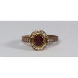 A 9ct gold cluster ring rub-over set with a central oval ruby surrounded by fourteen channel set